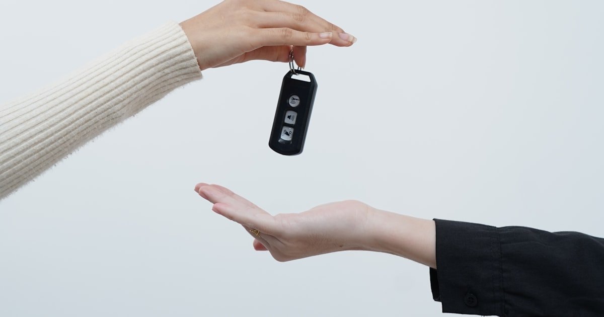 One person handing car keys to another after a loan is finalized