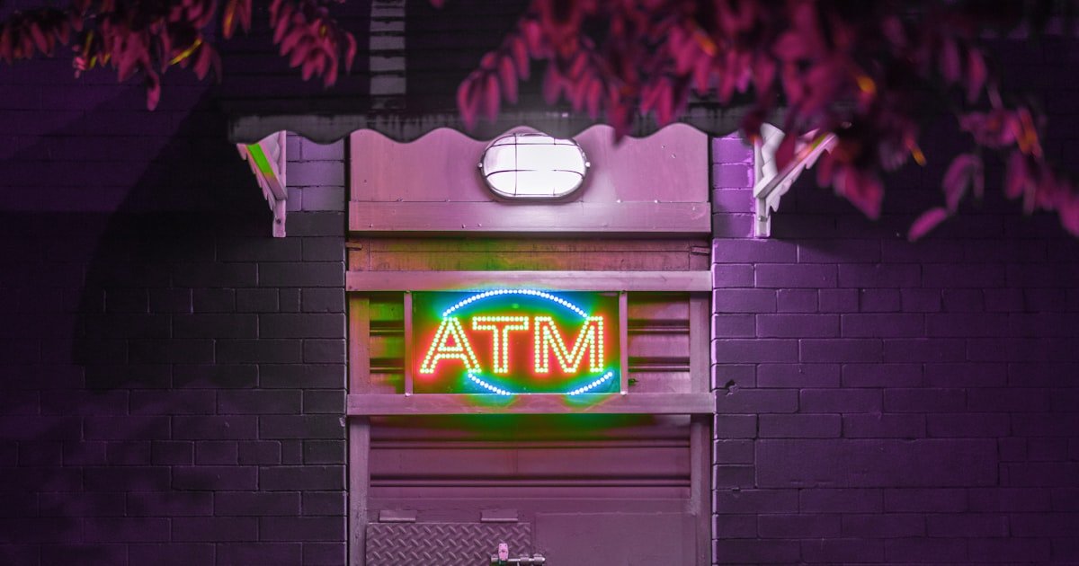 Illuminated ATM sign on a bank storefront at night