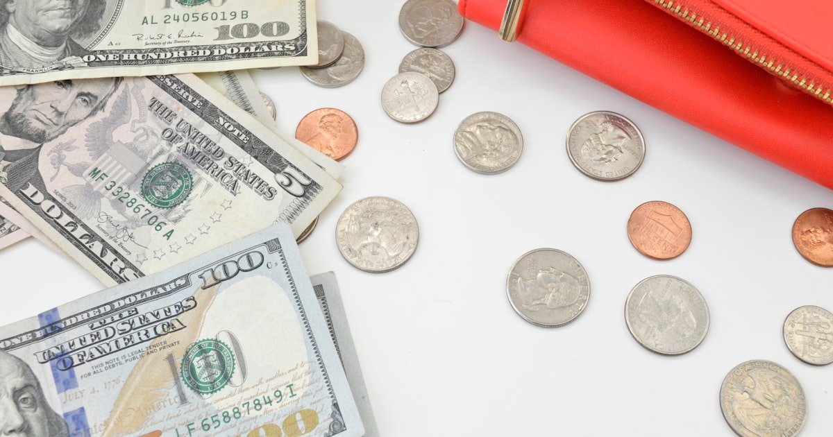 Cash and coins next to a red wallet, laid out for budgeting